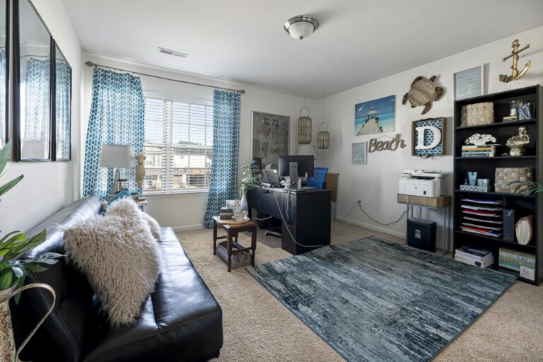 Stylish beach-themed living room with home office setup, combining comfort and functionality.